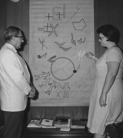 Kauffman, Earl Jr., Professor of Physical Education, pictured looking at tapestry, Public Relations Department
