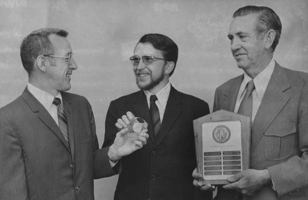 Klein, Hans Emil, pictured (center), of Dillingen/ Donau, West Germany, a graduate student at the University of Kentucky, has been named recipient of the Wall Street Journal student achievment award, he receives the medallion from Cludel Irwan, Associate Dean of the College of Business and Economics, Klein's name will be added to the plaque held by Herman A. Ellis Associate Professor of Business Administration