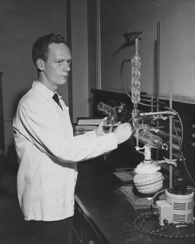 O' Brien, George, of Chicago Research Assistant in the University of Kentucky Chemistry Department, pictured at work in lab where compounds are being prepared to be used in the treatment of cancer, the chemistry department is co-operating with a clinic in Washington, DC on this project