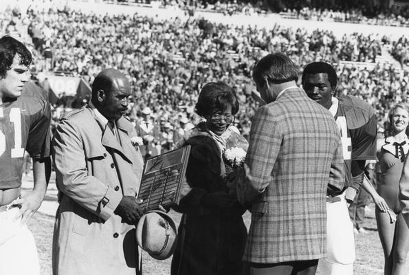 Page, Greg, one of the first African Americans to play football for the University of Kentucky, he was fatally injured during football practice due to a tragic accident, the University of Kentucky honored him by naming Greg page Apartments after him, pictured with parents at Commonwealth Stadium on parents' night