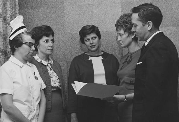 Rowe, Harold Ronald, Research Associate in Vocational Education, pictured from left to right, Mrs. Kenneth Flowers, a professional nurse; Mrs. Julian Parker, a physical therapists; Mrs. Robert H. Spedding, an inactive dental hygenists; and Rowe, of the Health Manpower Project, are all discussing the need for inactive health professionals to return to duty in Kentucky, from Public Relations Department