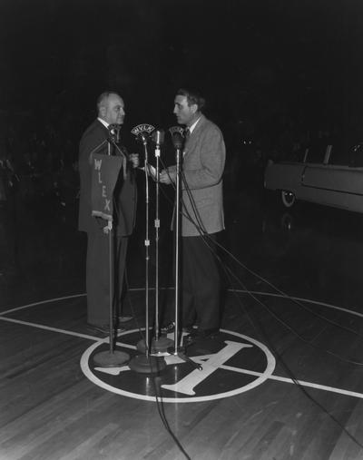 Rupp, Adolph, University of Kentucky Basketball Coach 1930-1971, pictured with J.B. Faulconer of WLEX Radio, master of the ceremony, giving Ripp new Cadillac being drinven into Memorial Colleseum