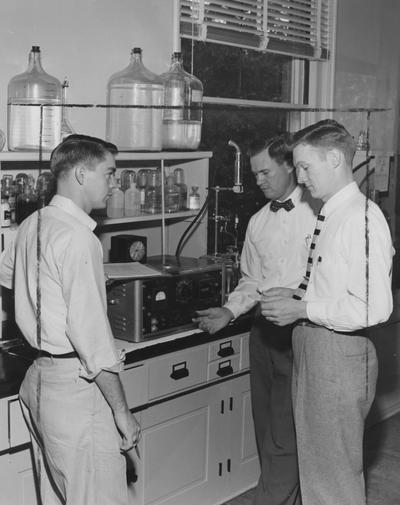 Seay, Wiliam Albert, Dean of College of Agriculture, Professor of Agronomy and Home Economics, Acting Director of Agriculture Experimation Station (1958-1962), pictured with two students second from right, showing two graduate students how to 