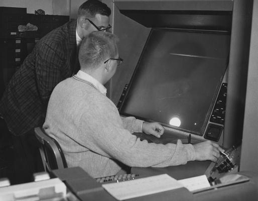 Vittitoe, Charles N., graduate student in physics at the University of Kentucky, pictured wroking on a new electronic measuring device in calculating actions of subatomic particles previously photographed by another device, the machine is only the second of its kind