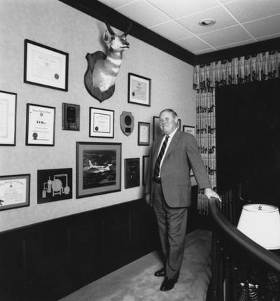 Whalen, S. J. Sam, Professor of Metallurgical Engineering, pictured standing by wall with plaques, certificates, and unknown mounted animal