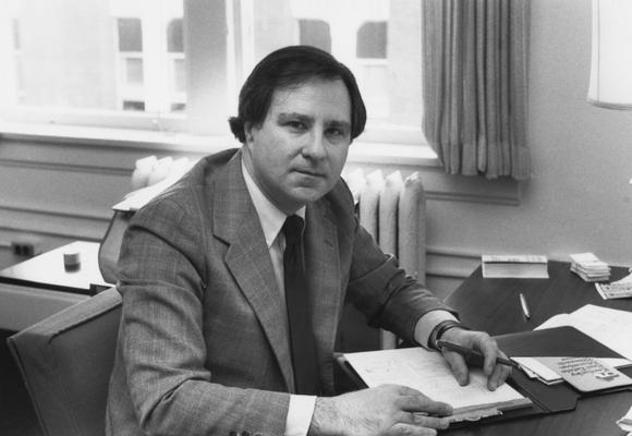 Wolff, John C., 1970 alumnus, Assistant Professor of Finance pictured sitting at desk in office