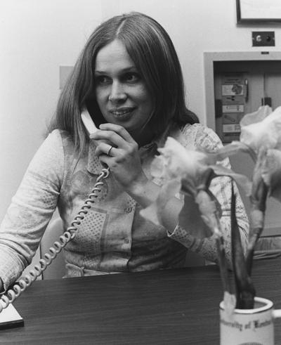 Unidentified woman sits at a desk and talks on a phone in the Medical Center