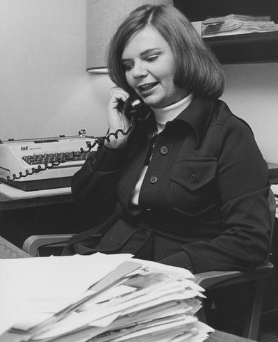 Unidentified woman sits at a desk and talks on a phone in the Medical Center