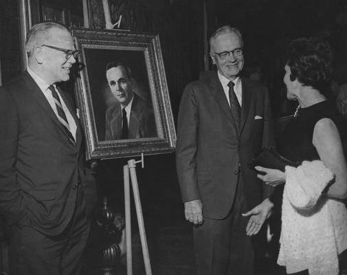 Carpenter, Cecil C., Professor, Economics, College of Commerce, Photo of dinner honoring Dr. Carpenter, pictured with LeRoy Miles, President of 1st Security National Bank and Trust Company, and unidentified woman, Painting presented by the Kentucky Bankers Association, Public Relations Department