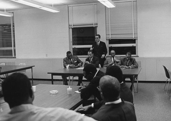 Charlesworth, Harold K., Professor, Business Administration, Director, Office of Development Service and Business Research, Associate Dean, College of Business and Economics, dates?, pictured delivering lecture at an Aid - to - Small Business meeting, June 26, 1969, Men seated at table (left to right) are Walter Brown, Executive Director, Lexington Urban League, Edgar Wallace, Lexington businessman, Jerome Hutchinson, Loan Officer for the Louisville Office of the Small Business Administration, Dr. Gus Ridgel, Chairman, Department of Economics, Kentucky State College