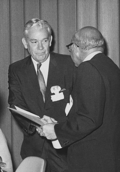 Coffman, Ben, Kentucky Assistant Superintendent of Education and Publication Director of the Bureau of Rehabilitation Services, pictured accepting award from William Loader, Public Relation Director of WHAS, at the annual University of Kentucky Special Education Dinner, August 5, 1970, Public Relations Department