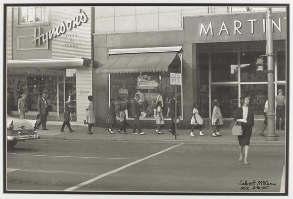 Children and adults marching down Lexington's Main Street in front of the stores Hymson's and Martin's