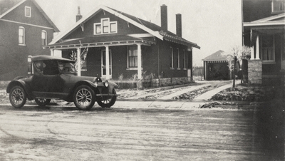 An image of a Model A Ford automobile and a one and a half story house (same house as in image 15) in the background. This image was found pasted on the back of page 100 of 