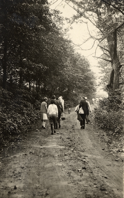 An image of several men and women walking on a dirt road