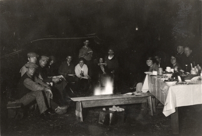 An image of a group of people sitting around a camp fire grilling corn. The people in the print include Margaret Ingels, 