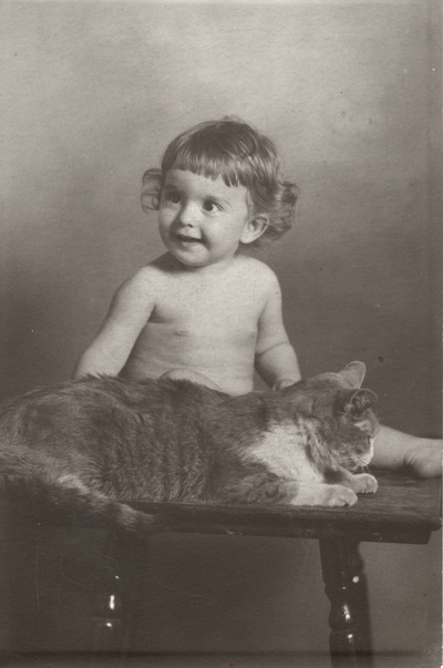 A portrait of a baby sitting a stool with a cat. This print was found among the 