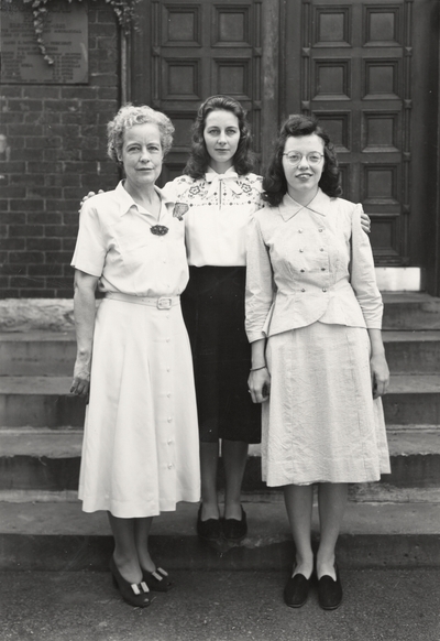 A group portrait of Margaret Ingels, Jessie Marie Kempier and Betty Carolyn Peters standing front of the entrance to Mechanical Hall on the University of Kentucky campus