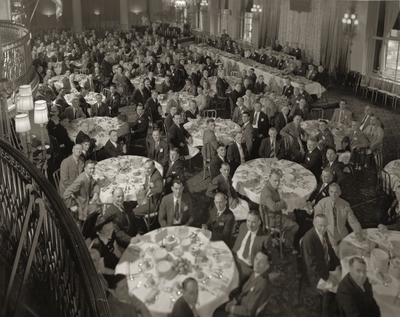 A group portrait of the anniversary dinner of Carrier Corporation in Syracuse, New York. Margaret Ingels is portrayed sitting at a table near the center of the room