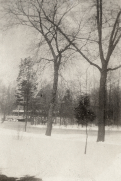 An image of a snow covered landscape with trees in the foreground and a train station in the background. This print was found pasted to the front of page 115 of 