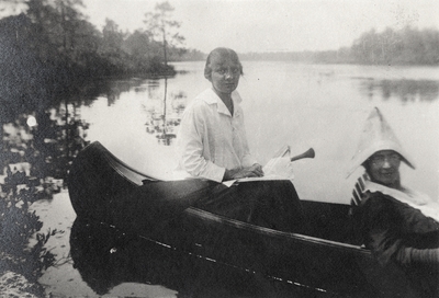 A portrait of two women in a canoe and writing on the print that says, 