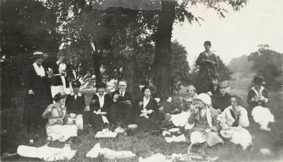 A group portrait of people having a picnic outdoors. This print was found pasted to the front of page 111 of 