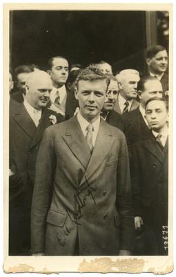 Portrait of Charles A. Lindbergh, American aviator, engineer, and Pulitzer Prize winner , standing with dignitaries. Autograph says 