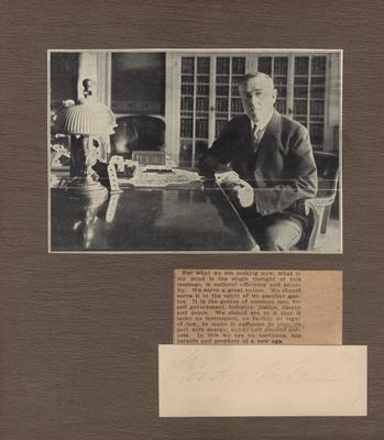 Portrait of Woodrow Wilson, sitting at a desk, with hand written autograph