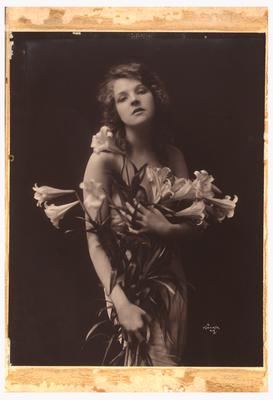 Photograph of woman standing holding flowers to cover her body. (Item numbers 517-519 were originally matted together in one frame. 517 on the left, 518 in center, and 519 on the right)