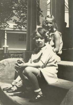 Two unidentified young girls sitting on steps