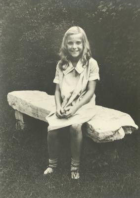 Unidentified young girl sitting on a stone bench