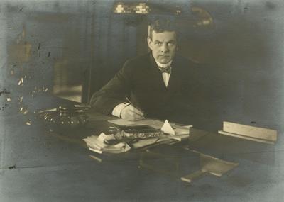 Portrait of an unidentified man sitting at a desk