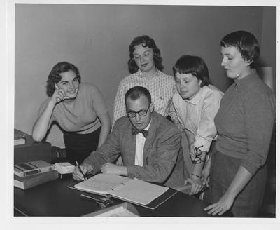 Newly elected officers of Guignol Players and their sponsor plan for the 1956 - 1957 theater season; From left to right: Vicki Arrington, Louisville vice - president; Jackie Mundell, Lexington treasurer; Suzanne Shively, Lexington president; and Frances Nave, Lexington secretary; with Ernest L. Rhodes, seated