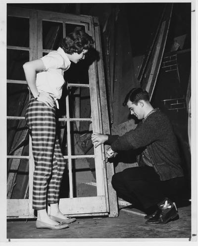 Steve Clark (right) is working and talking to Barbara Zweifel (left) backstage of a play in the Guignol Theater; This photo is on page 6 of the 1960 K - Book (student handbook)