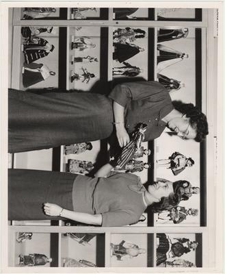 Two women look at a doll from the Rees Doll Collection