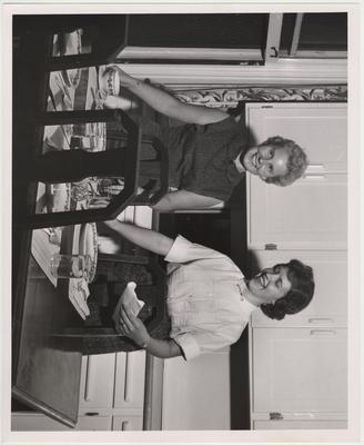 Setting a table in a dining room are Pat Clarke DeMarcus (left) and Norma Cable (right)