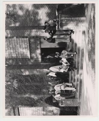 Students socializing outside of Lafferty Hall; Luther House, second man on far right