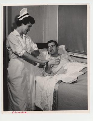 A nurse takes a patient's pulse and temperature in the infirmary