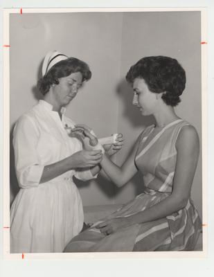 A nurse wraps a patient's wrist with gauze bandages