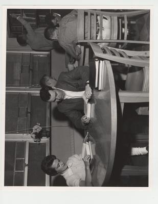 Students in the Pharmacy Library; From left to right: Betty Bernard, Melton H. Nichols, Russell Richie, Bob Reister (back to camera), Sherman McCubbin, and Dayle Rose (standing)