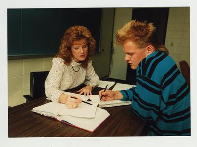 A woman helps a male student in a classroom at Ashland Community College