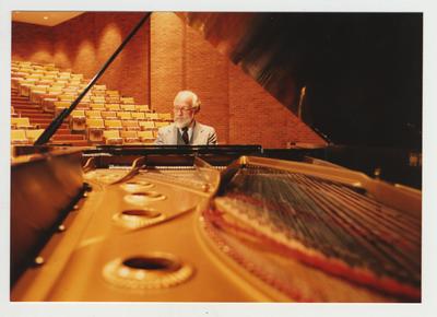 A man plays the piano in an auditorium