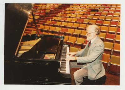 A man plays the piano in an auditorium