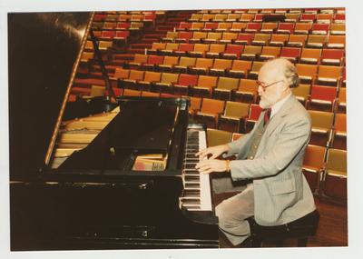 A man plays the piano in an auditorium