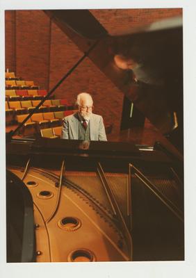 A man plays the piano in an auditorium