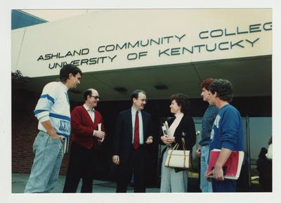 A group of people stand talking in front of Ashland Community College