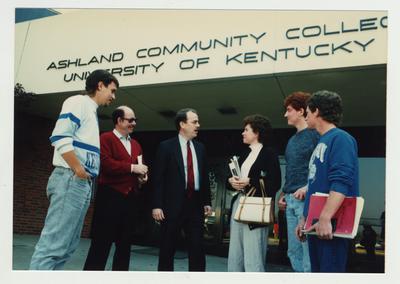 A group of people stand talking in front of Ashland Community College