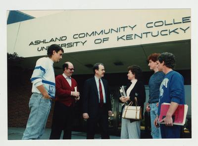 A group of people stand talking in front of Ashland Community College