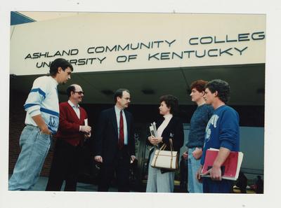 A group of people stand talking in front of Ashland Community College