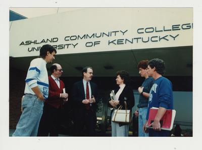 A group of people stand talking in front of Ashland Community College