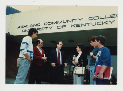 A group of people stand talking in front of Ashland Community College